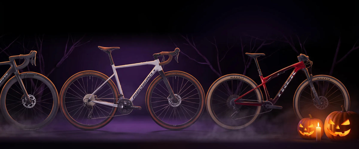 Tre biciclette in uno studio buio con zucche di Halloween